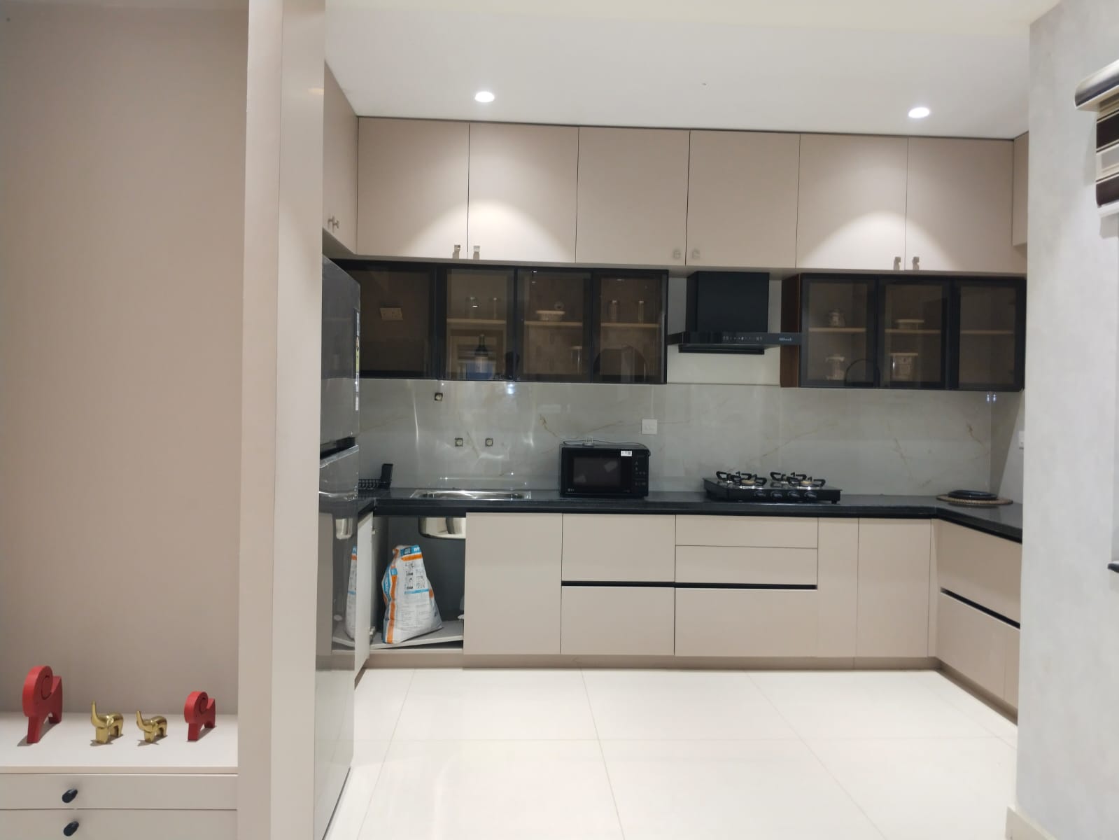 L-shaped modular kitchen with glass cabinets